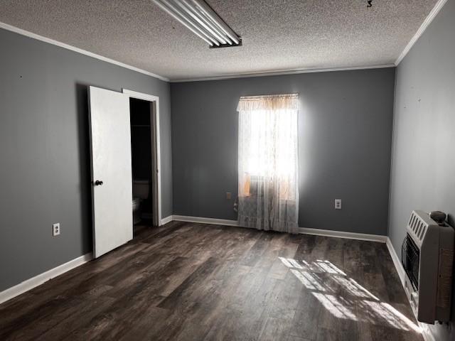 spare room with dark wood-type flooring, heating unit, and a textured ceiling