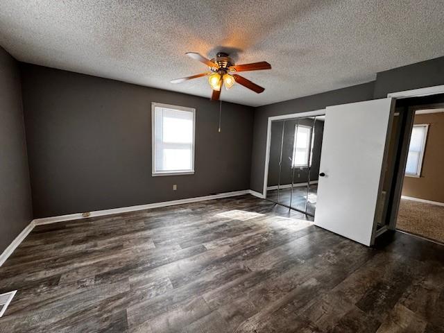 empty room with ceiling fan, dark hardwood / wood-style floors, and a textured ceiling