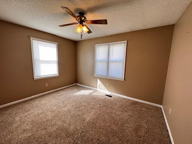 carpeted empty room featuring ceiling fan and a textured ceiling