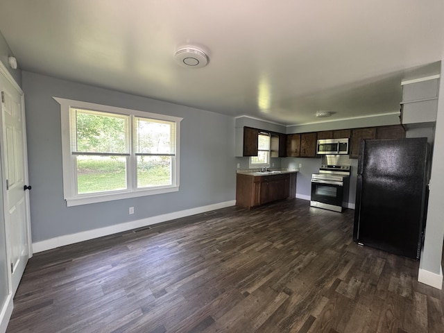 kitchen with dark wood-type flooring, light countertops, baseboards, and stainless steel appliances