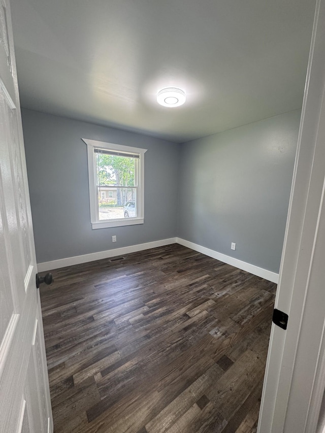 unfurnished room featuring baseboards and dark wood-style floors