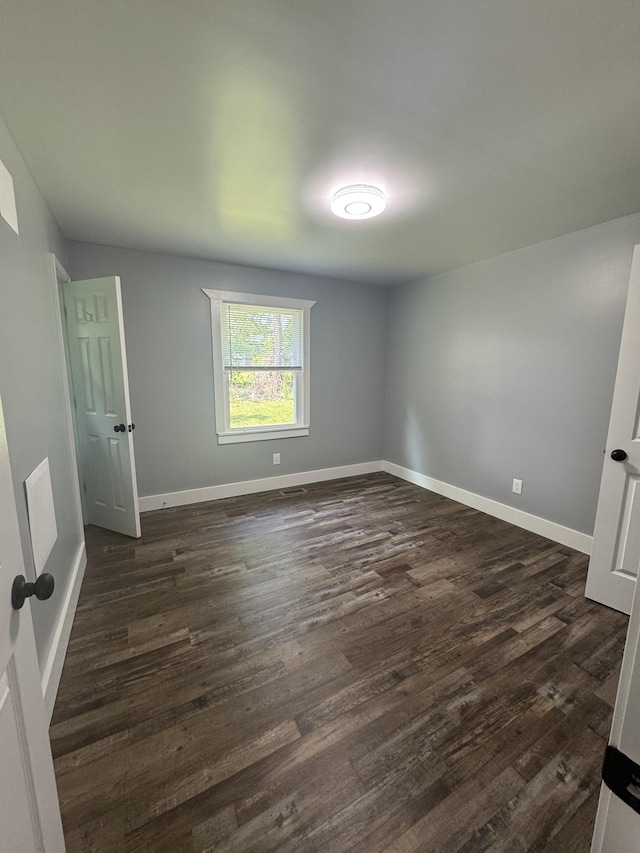 unfurnished bedroom featuring baseboards and dark wood-style floors