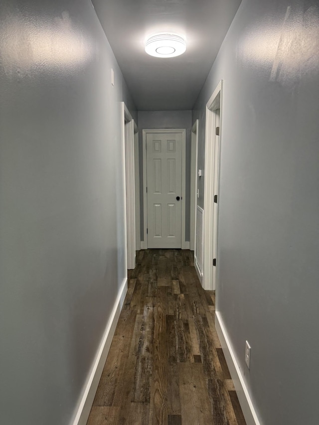 hall with baseboards and dark wood-type flooring