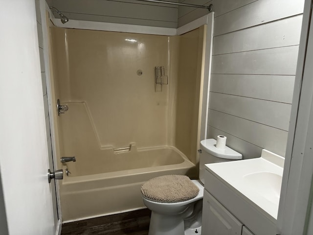 full bathroom with toilet, vanity, wooden walls, and  shower combination