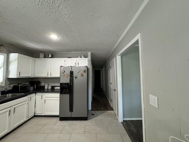 kitchen featuring sink, crown molding, light tile patterned floors, stainless steel refrigerator with ice dispenser, and white cabinets