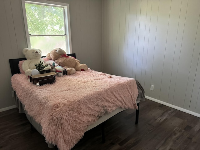 bedroom featuring wooden walls and dark hardwood / wood-style floors