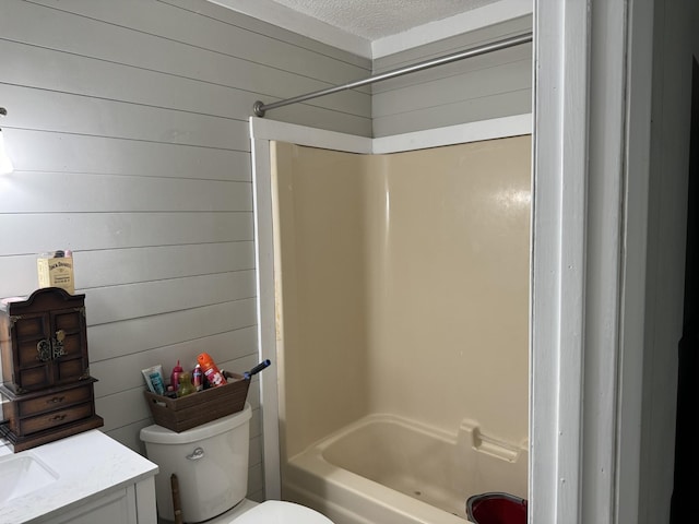 full bathroom with shower / bathing tub combination, vanity, a textured ceiling, toilet, and wood walls