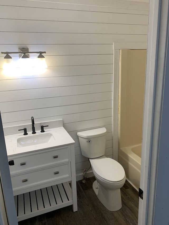 bathroom featuring vanity, hardwood / wood-style flooring, toilet, and wood walls