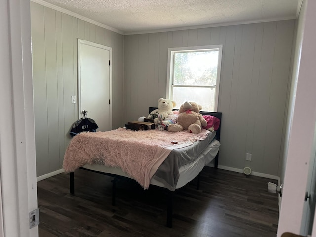 bedroom with dark hardwood / wood-style flooring, wooden walls, ornamental molding, and a textured ceiling