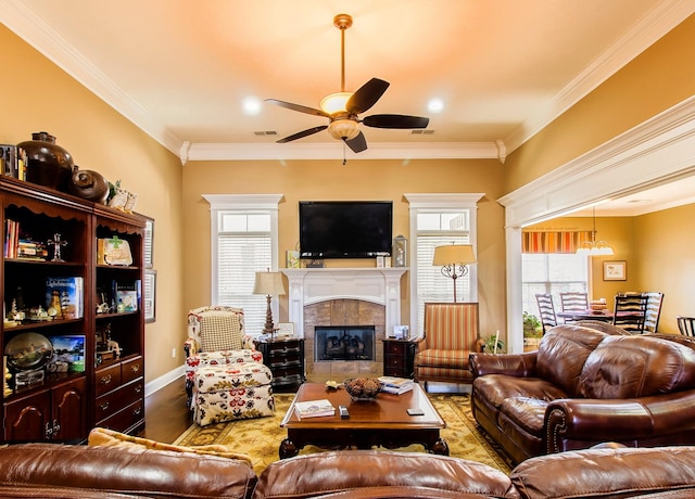 living room with hardwood / wood-style floors, crown molding, a tile fireplace, and ceiling fan