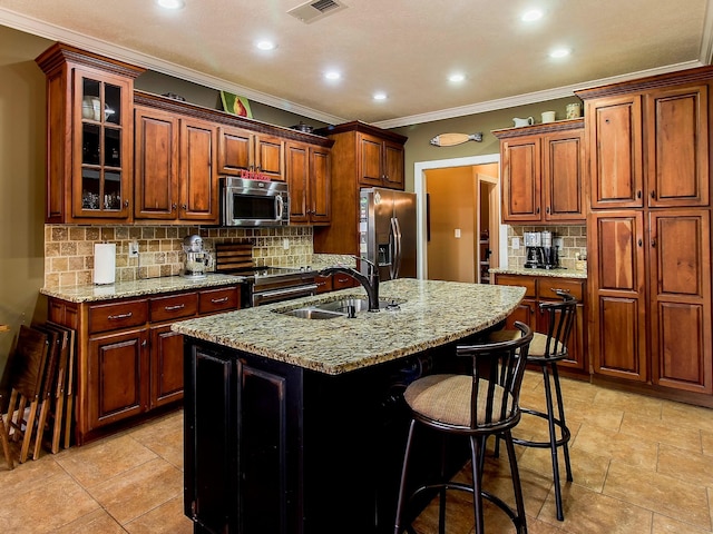 kitchen featuring sink, crown molding, stainless steel appliances, light stone counters, and a center island with sink