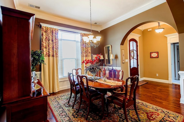 dining area with dark wood-type flooring, ornamental molding, a healthy amount of sunlight, and an inviting chandelier