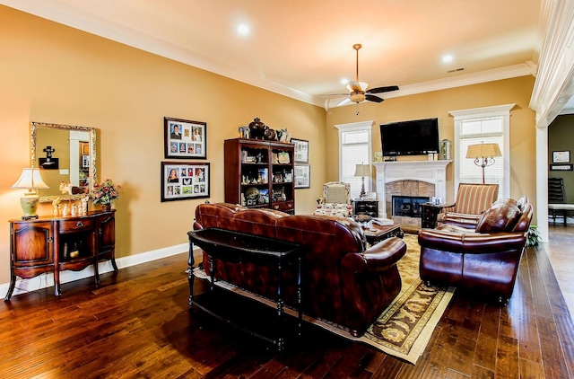 living room featuring ceiling fan, ornamental molding, dark hardwood / wood-style floors, and a tiled fireplace