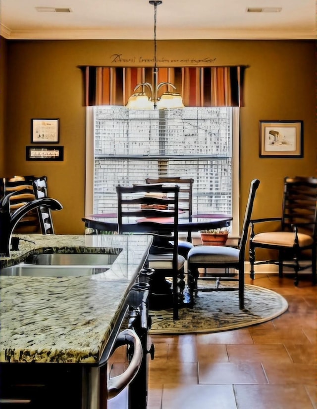 dining space featuring crown molding, sink, and a chandelier