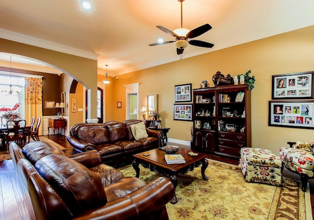 living room with hardwood / wood-style flooring, ceiling fan with notable chandelier, and ornamental molding