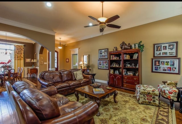 living room featuring hardwood / wood-style flooring, crown molding, and ceiling fan with notable chandelier