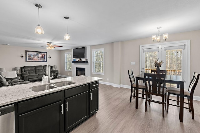 kitchen featuring pendant lighting, dishwasher, sink, and light stone countertops