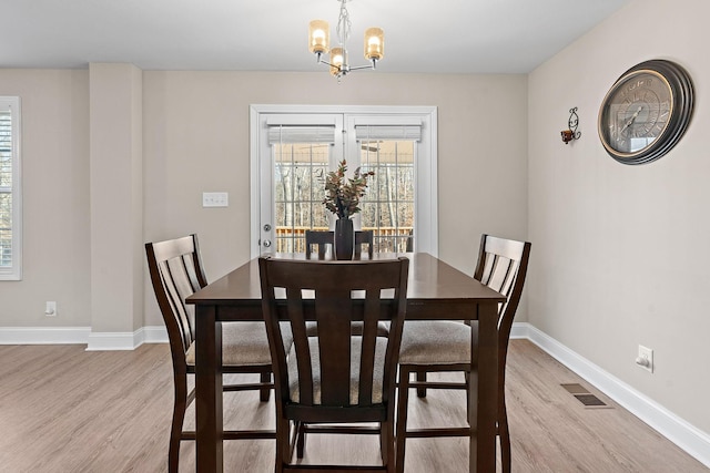 dining space featuring light hardwood / wood-style flooring and a notable chandelier