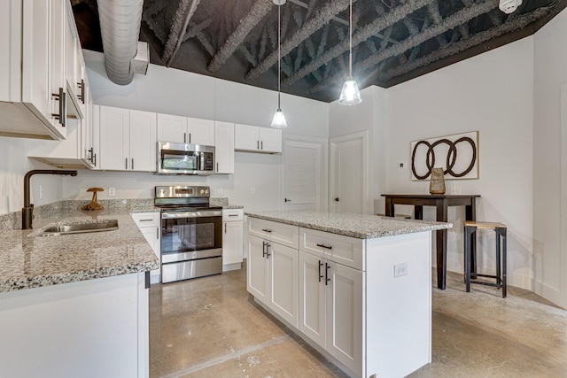 kitchen featuring a kitchen island, appliances with stainless steel finishes, decorative light fixtures, sink, and white cabinets