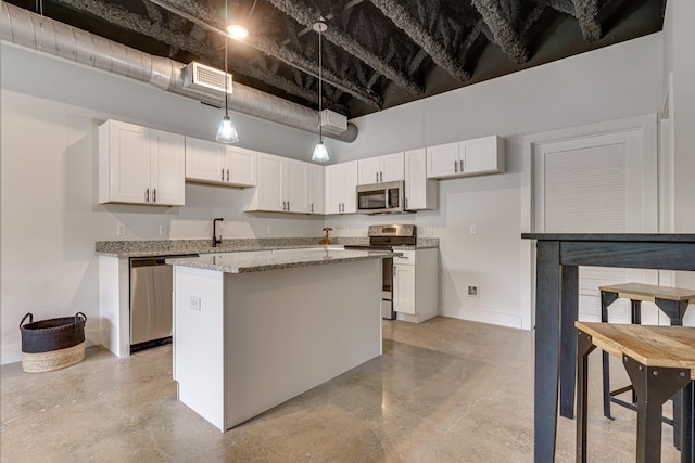 kitchen featuring a towering ceiling, pendant lighting, white cabinets, stainless steel appliances, and light stone countertops