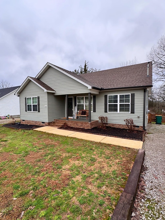 ranch-style house featuring covered porch and a front lawn