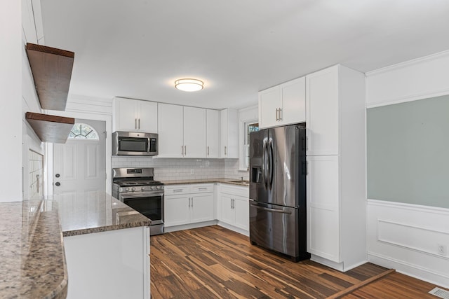 kitchen featuring white cabinetry, stainless steel appliances, dark hardwood / wood-style floors, and dark stone counters