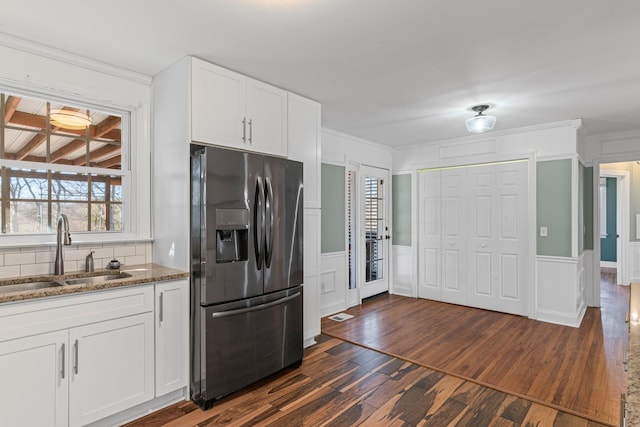 kitchen with sink, stainless steel refrigerator with ice dispenser, white cabinets, dark hardwood / wood-style flooring, and dark stone counters