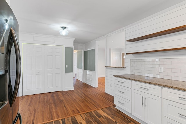 kitchen featuring refrigerator with ice dispenser, dark wood-type flooring, white cabinetry, backsplash, and dark stone countertops