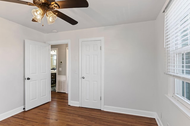 unfurnished bedroom featuring multiple windows, dark hardwood / wood-style floors, and ceiling fan