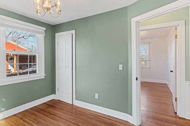 unfurnished bedroom featuring wood-type flooring, a notable chandelier, and a closet