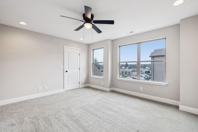 carpeted spare room featuring plenty of natural light and ceiling fan