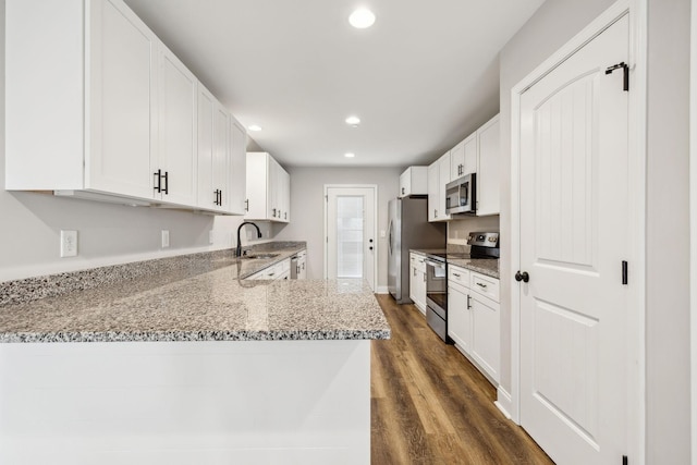 kitchen featuring white cabinetry, light stone counters, appliances with stainless steel finishes, dark hardwood / wood-style floors, and kitchen peninsula