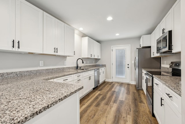 kitchen with stainless steel appliances, white cabinetry, sink, and light stone counters