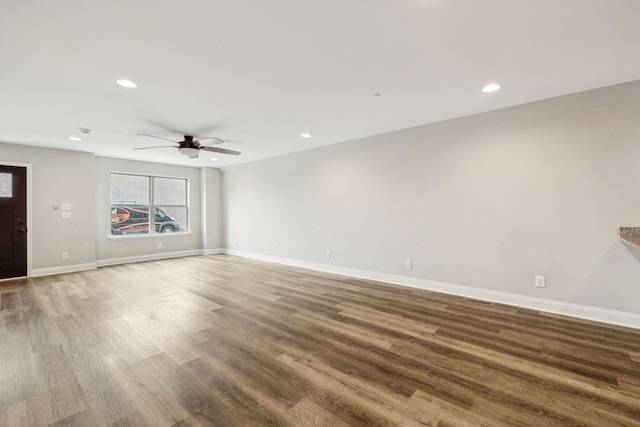 unfurnished living room featuring ceiling fan and dark hardwood / wood-style flooring