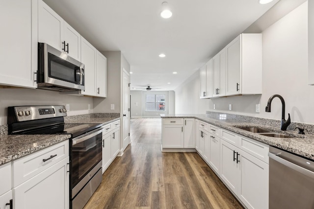 kitchen featuring sink, white cabinetry, appliances with stainless steel finishes, kitchen peninsula, and light stone countertops