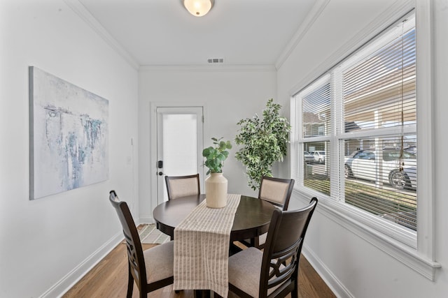 dining room with hardwood / wood-style floors, ornamental molding, and a healthy amount of sunlight