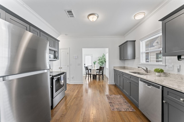 kitchen with sink, crown molding, gray cabinets, appliances with stainless steel finishes, and backsplash