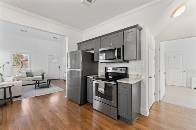 kitchen featuring crown molding, appliances with stainless steel finishes, gray cabinetry, tasteful backsplash, and dark hardwood / wood-style flooring