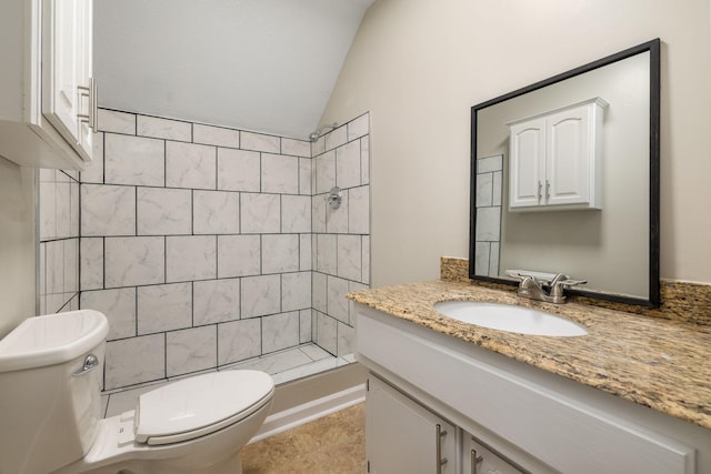 bathroom with tile patterned floors, lofted ceiling, toilet, a tile shower, and vanity