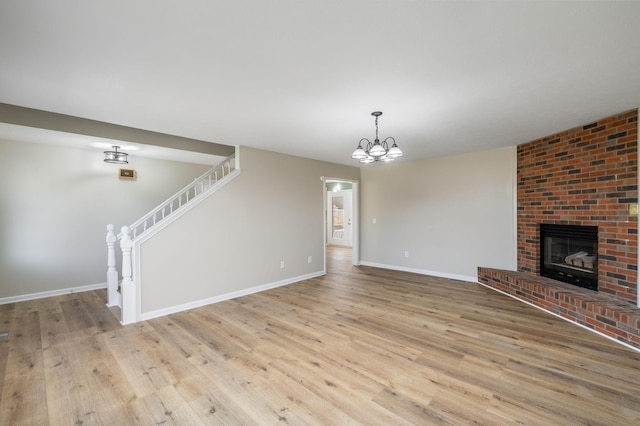 unfurnished living room with light hardwood / wood-style flooring, a fireplace, and an inviting chandelier