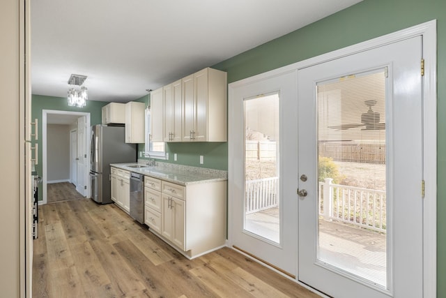 kitchen featuring french doors, sink, light stone counters, light hardwood / wood-style flooring, and appliances with stainless steel finishes