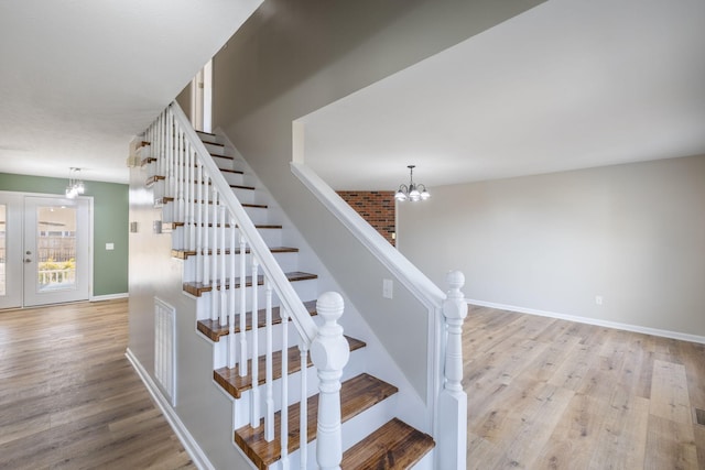 staircase featuring a notable chandelier, wood-type flooring, and french doors