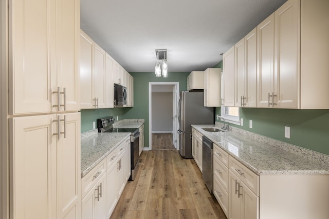 kitchen featuring light stone counters, appliances with stainless steel finishes, light hardwood / wood-style floors, and white cabinets