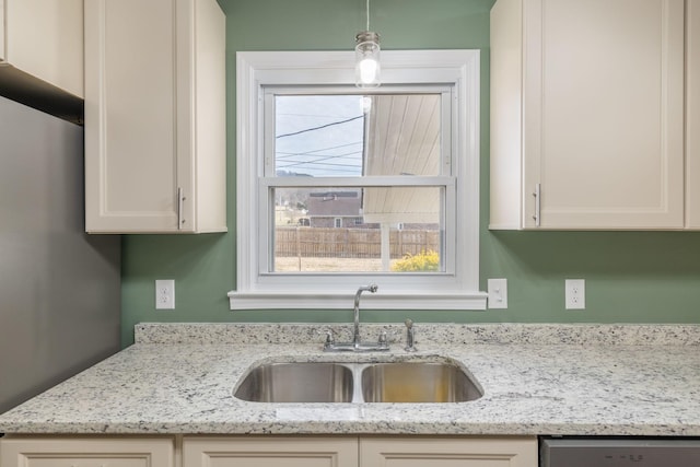 kitchen with decorative light fixtures, light stone countertops, sink, and dishwasher