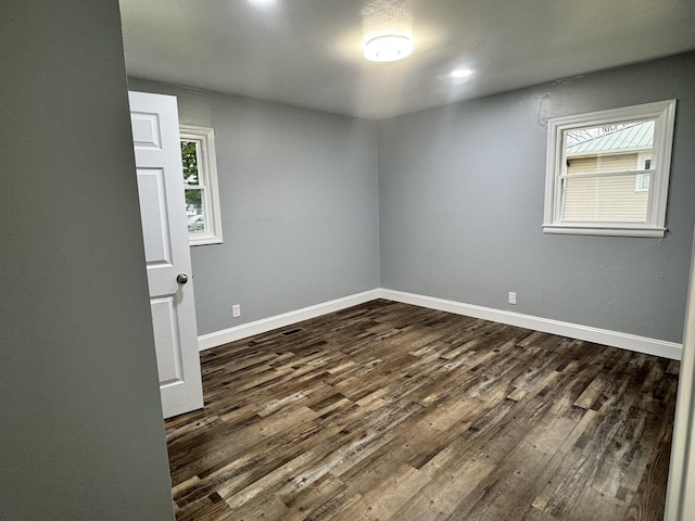 spare room with dark wood-type flooring and plenty of natural light