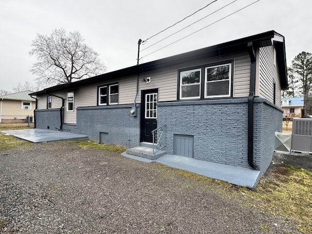 raised ranch featuring central AC unit and a patio area