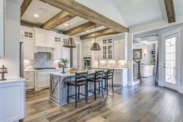 kitchen with white cabinetry, stainless steel oven, and an island with sink