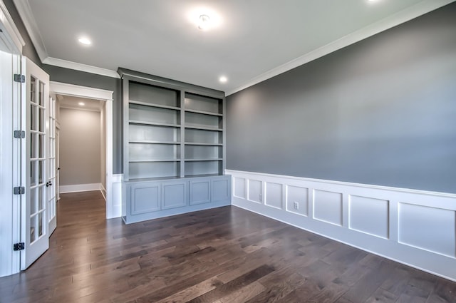 empty room featuring built in shelves, crown molding, and dark wood-type flooring