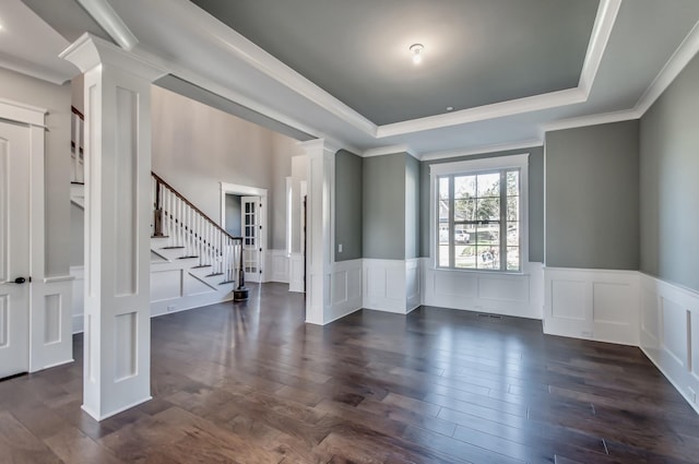 spare room featuring crown molding, dark wood-type flooring, and decorative columns