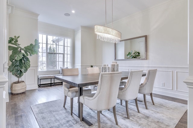 dining room with a notable chandelier, crown molding, wood-type flooring, and decorative columns